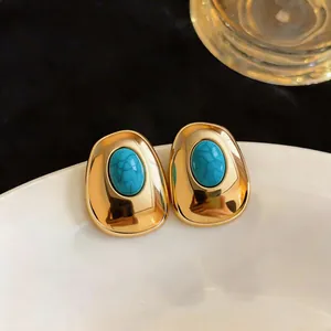 Close-up of elegant vintage gold-tone earrings featuring smooth oval turquoise resin stones