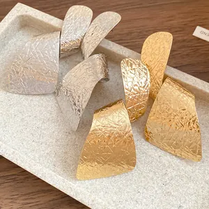 Detailed view of irregular textured metal earrings in gold and silver finishes