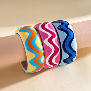 Close-up detail showing the smooth resin texture and vibrant colorful wavy patterns on bangles