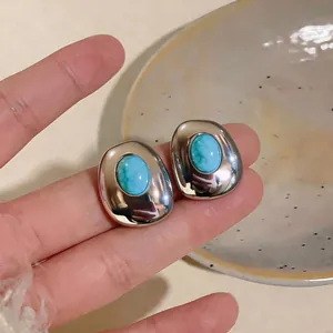 Close-up of vintage oval stud earrings with turquoise resin stone in silver finish