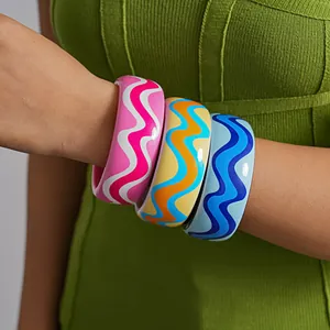 Detailed macro shot of three colorful dopamine-style resin wavy bangles on a model's arm