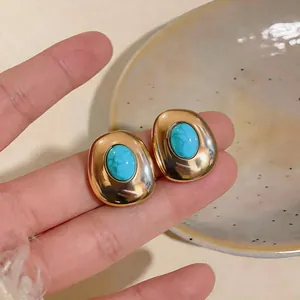 Detailed view of vintage gold oval stud earrings with turquoise resin center piece