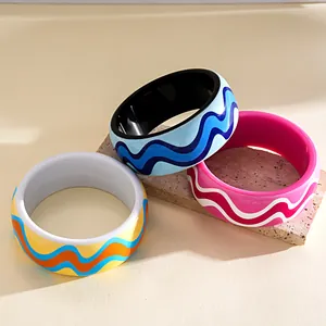 Detailed view of colorful resin bangles with vibrant wavy patterns and glossy finish