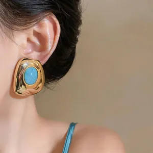 Close-up detail of a vintage gold geometric oval stud earring with turquoise resin inlay