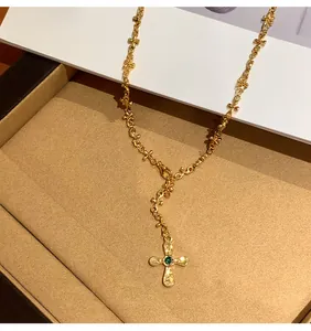 Primo piano dettagliato della collana a croce dorata con pietra verde centrale a forma di occhio