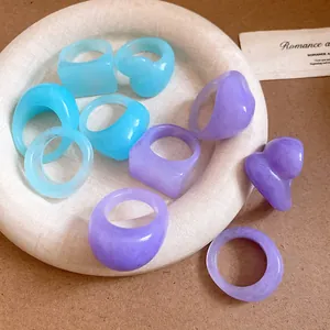 Close-up of minimalist resin rings in pastel blue and purple with a marbled texture.