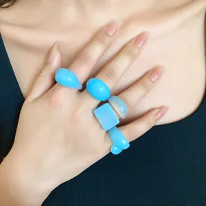 Detailed macro view showing the glossy texture of blue geometric resin rings on a hand
