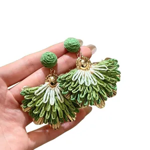 Handmade raffia fan-shaped drop earrings featuring green and white woven textures