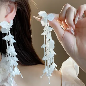 Elegante weiße Glasblumen-Quastenohrringe mit langen Perlensträngen Detailaufnahme.