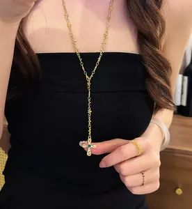 Elegante collana a croce dorata bohémien con ciondolo occhio verde indossata da modella