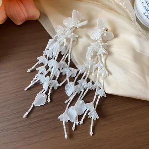 Nahaufnahme der eleganten weißen Glasblumen-Quastenohrringe mit 18 Karat Vergoldung