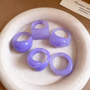 Close-up of five lavender resin rings with geometric shapes on a textured plate