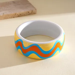 Detailed view of a thick colorful resin bangle with vibrant blue and orange wave designs
