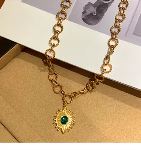 Primo piano di una collana a catena dorata vintage con ciondolo a sole in pietra verde