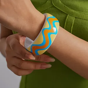 Close-up detail of a vibrant resin bangle featuring colorful wave patterns on wrist