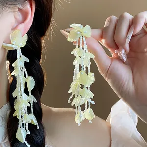 Detailansicht eleganter Glastropfenohrringe mit gelben Blüten und weißen Perlen