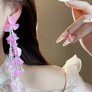 Nahaufnahme von eleganten lila Glasblüten-Quastenohrringen mit weißen Perlen am Modell