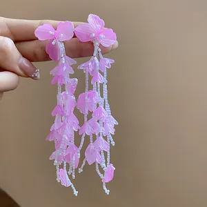 Detailansicht langer rosa Blumen-Quastenohrringe mit weißen Perlen und matten Blüten.