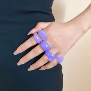 Close-up of stylish purple resin geometric rings worn on hand for creative accessory styling