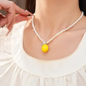 Elegante weiße Perlenkette mit zirkonbesetztem Harzzitronenanhänger an einem Modell