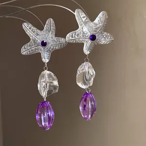 Detailed view of resin starfish earrings with purple beads and clear irregular accents.