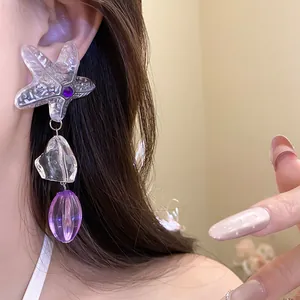 Close-up detail of a starfish drop earring with purple resin beads and silver needle