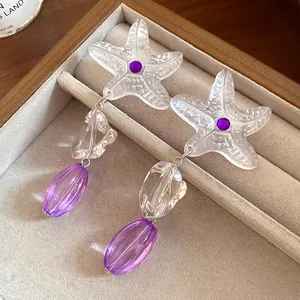 Detail shot of elegant resin starfish pendant earrings with purple gemstone accents
