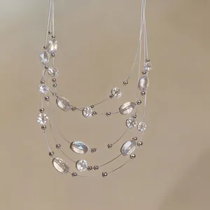 Bohemian multi-layer necklace with clear crystals and silver beads on a neutral background