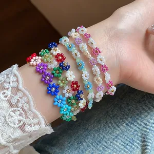 Vue détaillée de bracelets de fleurs en perles de verre colorées faits à la main sur un poignet