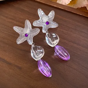 Detailed macro shot of clear resin starfish earrings with purple faceted beads.