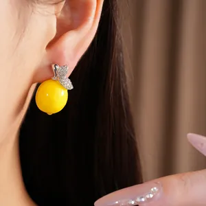 Gros plan de boucles d'oreilles citron en résine jaune avec détails en zircone