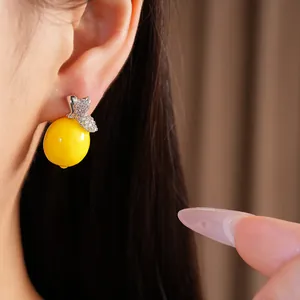 Vue détaillée d'une boucle d'oreille citron en résine jaune avec feuilles en zircon.