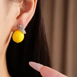 Gros plan d'une boucle d'oreille citron en résine avec des feuilles de zircon.
