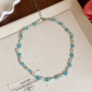 Gros plan d'un ras-du-cou en perles de verre avec de délicats motifs floraux bleus et blancs