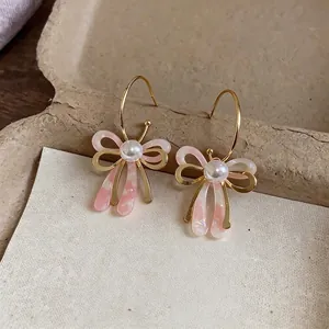 Élégantes boucles d'oreilles en forme de nœud doré avec perles blanches et fini rose