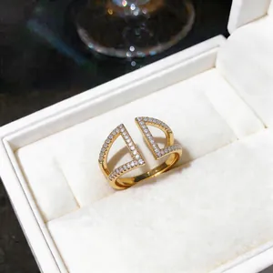 Λεπτομέρεια χρυσού γεωμετρικού ανοιχτού δαχτυλιδιού με αστραφτερές πέτρες ζιργκόν