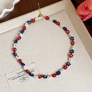 Détail d'un collier de fleurs en perles de verre fait main, rouge, bleu et blanc, été
