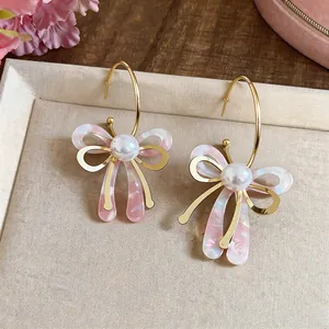 Gros plan détaillé montrant le design élégant du nœud rose marbré sur les boucles d'oreilles.