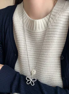 Close-up of elegant flower pendant necklace with pearl bead on silver ball chain