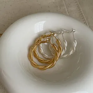 Primer plano de la textura esmerilada brillante en aros retorcidos dorados y plateados.