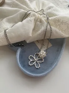 Close-up of silver-tone ball chain necklace with beaded flower and pearl cluster
