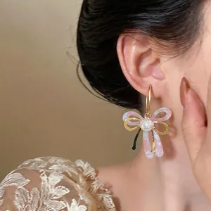 Détail rapproché de boucles d'oreilles perles nœud élégantes portées par un mannequin