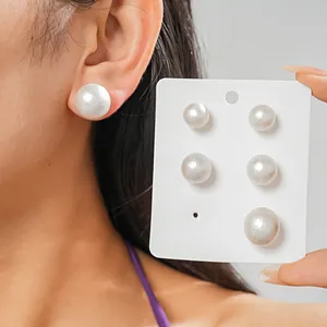 Primo piano di orecchini a perno con perle bianche di varie dimensioni su un orecchio