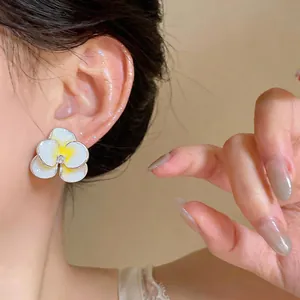 Primo piano di eleganti orecchini a lobo a fiore in smalto bianco e giallo con zircone