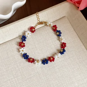 Détail d'un bracelet de fleurs en perles de verre tissé main aux pétales rouge blanc bleu