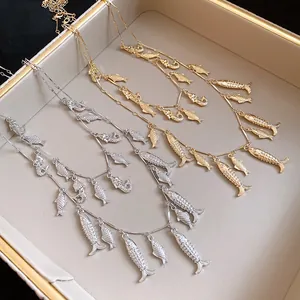 Gros plan de colliers à plusieurs rangs avec des breloques poissons en argent et en or.