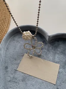 Detail view of a silver-toned pearl flower necklace featuring a textured hollow pendant