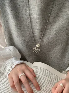 Detail shot of a silver flower necklace with pearls and matching rings on a model.