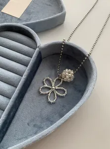 Macro view of a Korean style pearl flower pendant necklace in a blue velvet jewelry box
