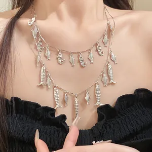 Gros plan d'un collier rétro à double rangée avec de multiples pendentifs poissons argentés.